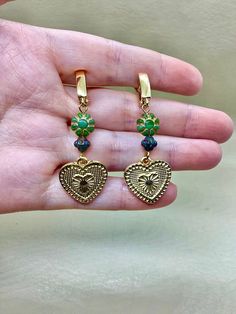 Get ready to fall in love with our Cactus and Succulent inspired earrings. These boho chic earrings feature Czech pressed daisy bicone spacer beads in dark Picasso with a light sheen, paired with small flower daisy green in gold wash beads. The 18x19mm 24k Shiny Gold Plated Heart Charms add a touch of elegance to these earrings, which are finished in 18 carat plated gold. Measuring 6 cm in length with a 2 cm by 2 cm heart charm, these earrings are lead, cadmium, and nickel free. Complete your lo Handmade Green Jewelry For Valentine's Day, Dangle Heart Earrings As Gift, Bohemian Drop Heart Earrings For Gift, Bohemian Style Heart Drop Earrings For Gift, Nickel-free Dangle Heart Earrings For Festivals, Festival Drop Earrings With Dangling Charms, Festival Jewelry Drop Earrings With Dangling Charms, Festival Jewelry With Dangling Drop Earrings, Green Heart-shaped Bohemian Earrings