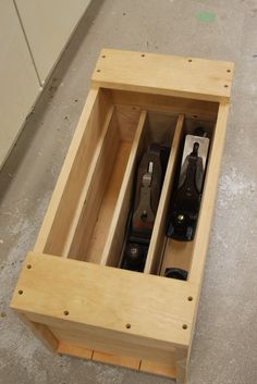 an open wooden box with two bottles in it sitting on the floor next to cabinets