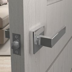 a close up of a door handle on a wooden door with a couch in the background