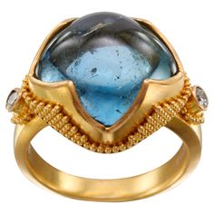 A luscious, bright blue 13 mm cushion shaped aquamarine cabochon is held diagonally in our signature "4 point with jawan" handmade high karat gold design. Stacked geometric "jawan" granulation adorn the sides of the bezels and two 1.8 mm VS1 accent diamonds are set on the sides. The comfortable flat tapered matte-finish shank is currently size 6.5. It is resizable. One of our most popular designs, this rich blue stone and ring is a stunner! You won't be disappointed! Aquamarine Cabochon, 22k Gold Ring, Popular Designs, Comfortable Flats, 3 Carat, 22k Gold, Gold Design, Blue Stone, Cocktail Rings