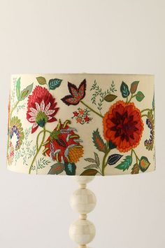 a lamp with flowers and butterflies painted on the lampshade is sitting on a table