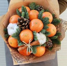 a bouquet of oranges and pine cones in a paper bag