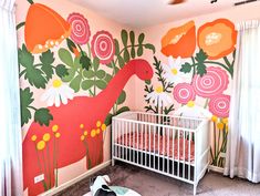 a baby's room decorated in pink, orange and green with flowers on the wall