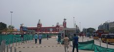 several people are walking around in front of a building with green tarp covering it