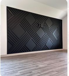 an empty room with wood flooring and black wall art on the wall behind it