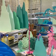 many different colored paper sculptures in a room with other items on the floor and behind them