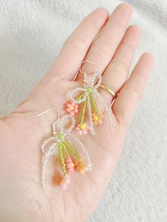 the hand is holding three small beads on it's fingers, and there are flowers hanging from them