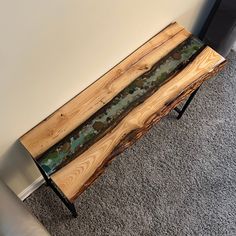 a table made out of wood and glass with metal legs on carpeted flooring