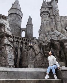 a woman is sitting on the steps in front of hog potter's castle at universal studios