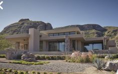 a large house in the middle of a desert with mountains in the backgroud