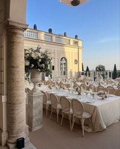 an outdoor dining area with tables and chairs set up for a formal function in front of a large building