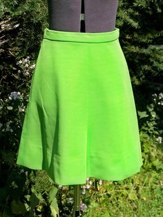 "This vintage 1970s \"Flip Skirt\" has been custom-made of easy care spring green acrylic double-knit fabric. This was the miracle fabric of the time. It was called a \"Flip Skirt\" because it has a slight flare out at the bottom and seems to flip as you walk. This skirt has a waistband and a nylon zipper on the left side. A hook waist closure closed the waistband. It has seams center front and center back with 2 back darts for shaping. Actual color is not as neon green as in the photo. Its a ni Retro Green A-line Skirt, Fitted A-line Green Skirt, Vintage Stretch Green Bottoms, Vintage Green Skirt For Spring, Vintage Green Full Skirt Bottoms, Vintage Green Full Skirt, Vintage Fitted Green Skirt, Style Vert, Mod Look