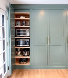 a kitchen with green cabinets and wooden floors