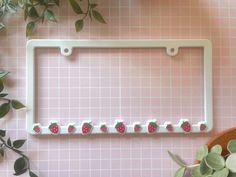 a white license plate frame with strawberries on it and green leaves next to it