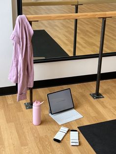 an open laptop computer sitting on top of a wooden floor next to a pink cup