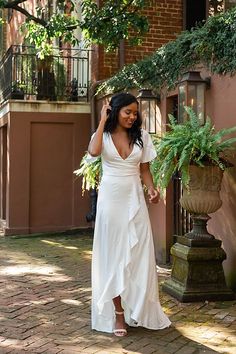 a woman in a white dress is walking down the street with her hand on her head