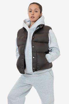 This made in U.S.A. puffer vest is the perfect layering piece for Los Angeles winters. Composed of a super fluffy polyester filling with a 100% nylon shell, this style features a reinforced snap-button closure, and 2 large pockets. We gave this style a wide, boxy fit with a mockneck for essential warmth. Try sizing up for an even more oversized fit. Made in Los Angeles, Calif. Our experienced sewers earn up to $25 an hour and no less than $16; additionally workers have healthcare benefits for le Sleeveless Down Puffer Vest, Nylon Vest For Layering In Fall, Fall Nylon Vest For Layering, Fall Layering Nylon Vest, Sporty Winter Vest For Layering, Nylon Vest For Winter And Cold Weather, Nylon Vest For Cold Weather And Winter, Sleeveless Nylon Puffer Jacket For Cold Weather, Winter Streetwear Puffer Vest