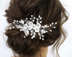 a woman wearing a bridal hair comb with flowers and leaves on it's side