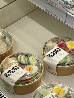 three round containers filled with cucumbers on top of a counter next to each other