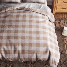 a bed with brown and white checkered comforter on top of it next to a night stand