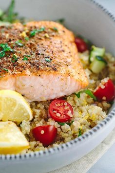 a close up of a bowl of food with salmon, rice and veggies