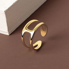 a gold ring sitting on top of a brown table next to a white box with a black object in it