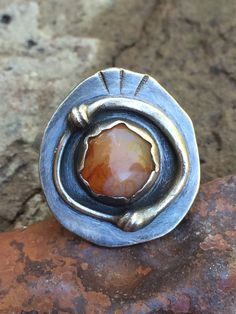 "This unique metalwork ring features a lovely polished agate pebble that was collected from the Oregon coast. The setting is made by hand from fine (.999) and Sterling (.925) silver. The silver has been oxidized and then polished to highlight certain areas of interest on the detailwork of the metal. This ring is perfect for fall and has a modern BOHO vibe. The ring in the photos has sold. Your ring will be made in the same style but expect some slight variances in texture and stone shape (they'r Handcrafted Oval Moonstone Ring, Handmade Artisan Oval Moonstone Ring, Artisan Moonstone Ring With Natural Stones, Unique Carnelian Jewelry With Large Stone, Artisan Hand Forged Oval Ring, Artisan Moonstone Ring, Agate Jewelry With Large Stone For Anniversary, Artisan Hand Forged Rust Jewelry, Unique Oval Opal Ring For Jewelry Making