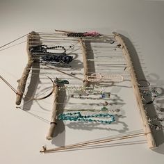 an assortment of bracelets and necklaces are displayed on a white surface with wood sticks