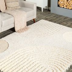 a living room with a couch, chair and rugs on the wooden floor next to a fire place