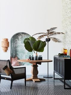 two chairs and a table in a room with plants on the wall behind them,