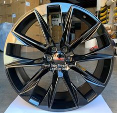 a black wheel with chrome spokes on display in a storeroom, ready to be painted