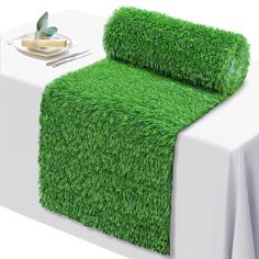 a bed covered in green grass next to a white table