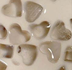 several heart shaped ice cubes are in a milk mixture with brown and white colors