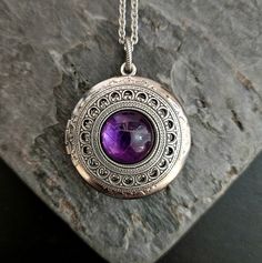 A beautiful purple amethyst centered on an intricate, antiqued silver filigree and set on an antiqued silver locket. Locket hangs from an antiqued silver chain. Locket opens with 2 spaces for pictures or things as shown.  Details: Locket measures 32mm in diameter Locket has a smooth back as shown  Locket and chain are plated brass Necklace measures 24 inches  Stones are genuine amethyst  Want a shorter chain? Just leave a note to seller at checkout for me and I can adjust it for you, no extra charge.  Please allow for possible slight color differences due to different settings on different screens.  Thank you for shopping Delicate Industry :) Necklace Gift Ideas, Art Deco Locket, Chain Locket, Crystal Locket, Aesthetic Jewellery, Silver Locket, Gift Ideas For Her, Silver Lockets, Amethyst Jewelry