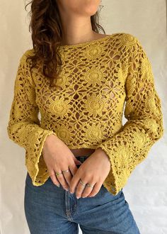 a woman is wearing a yellow top with crochet on the shoulders and long sleeves