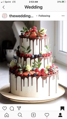 a three tiered cake decorated with fresh berries and chocolate drizzle