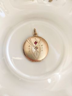 Beautiful antique gilt brass locket, set with two small stones in pink and clear glass. The colour of the locket appears to be slightly more rose gold on the pictures than in reality. The locket is nicely engraved.  The jewel is in overall good antique condition, but there are traces of wear due to its age: some scratches and traces of oxidation, especially on the sides and back. The locket closes well and looks very nice worn.  Dimensions: approx. 3.3 cm (with clasp) x approx. 2.5 cm diameter. Gold Pendant Locket Necklace With Birthstone, Rose Gold Pendant Locket Jewelry, Rose Gold Locket Pendant Jewelry, Formal Rose Gold Locket Pendant Necklace, Formal Rose Gold Locket Necklace, Rose Gold Locket Necklace For Formal Occasions, Antique Gold Victorian Locket Jewelry, Victorian Yellow Gold Pendant Locket Necklace, Victorian Rose Gold Locket Jewelry