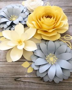 paper flowers are arranged on a wooden surface with yellow and gray petals in the center