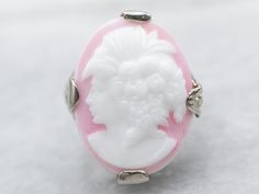 a pink and white ring with a woman's head on it, sitting on a table