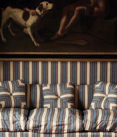 a striped couch in front of a painting with a dog on it's back