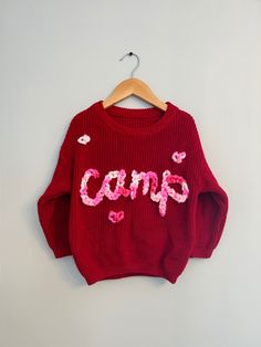 Valentines Custom Knit Sweater! The cutest hand embroidered sweater with a pink multicolor chunky yarn on an red sweater.  Sweaters are an oversized fit. Model is wearing 18-24 months sweater (but typically wears 18 month clothing). Stay true to size for baggy fit that will last even longer!  CARE: wash normal (recommended inside out but not necessary) and lay flat to dry to avoid yarn fuzzing.  For more info, questions, changes or customs- message us on here or on instagram @ campcoveco! Cute Acrylic Sweater For Fall, Cozy Red Cotton Sweater, Pink Knit Sweatshirt, Cute Cotton Chunky Knit Sweater, Playful Red Sweatshirt For Fall, Cute Red Long Sleeve Sweater, Cute Chunky Knit Sweater For Fall, Pink Cotton Knit Sweater, Playful Pink Winter Sweater