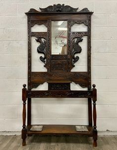 an old wooden bench with mirror on top and shelf below it in front of a brick wall