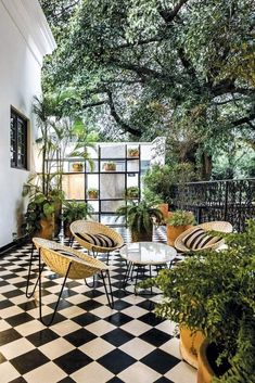 an outdoor patio with black and white checkered flooring, potted plants and tables