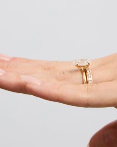 a woman's hand holding an engagement ring with a diamond on top and side