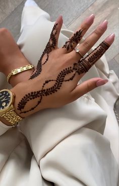 a woman's hand with hennap and rings on her left wrist, holding a watch