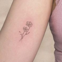 a small flower tattoo on the left arm