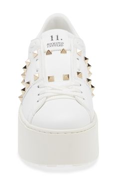 Signature pyramid studs shine across the leather upper of this Italian-crafted platform sneaker refined with an innovative lacing technique. 2" heel (51mm); 1 1/2" platform (size 38.5) Lace-up style Leather upper and lining/synthetic sole Made in Italy Designer Shoes Luxury Studded Platform Sneakers With White Sole, Luxury Low-top Platform Sneakers With Studded Outsoles, Luxury Leather Platform Sneakers With Studded Outsoles, Designer Studded Low-top Sneakers, Luxury Studded Lace-up Sneakers, Silver Studded Low-top Sneakers, Designer Low-top Platform Sneakers, Low-top Leather Sneakers With Rivets, Valentino Rockstud