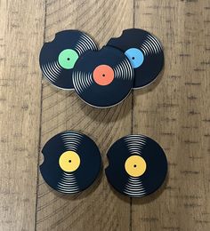 four vinyl record coasters sitting on top of a wooden table