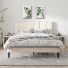 a white bed sitting in a bedroom next to two pictures on the wall above it