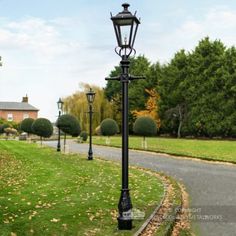 an old fashioned lamp post in the middle of a park